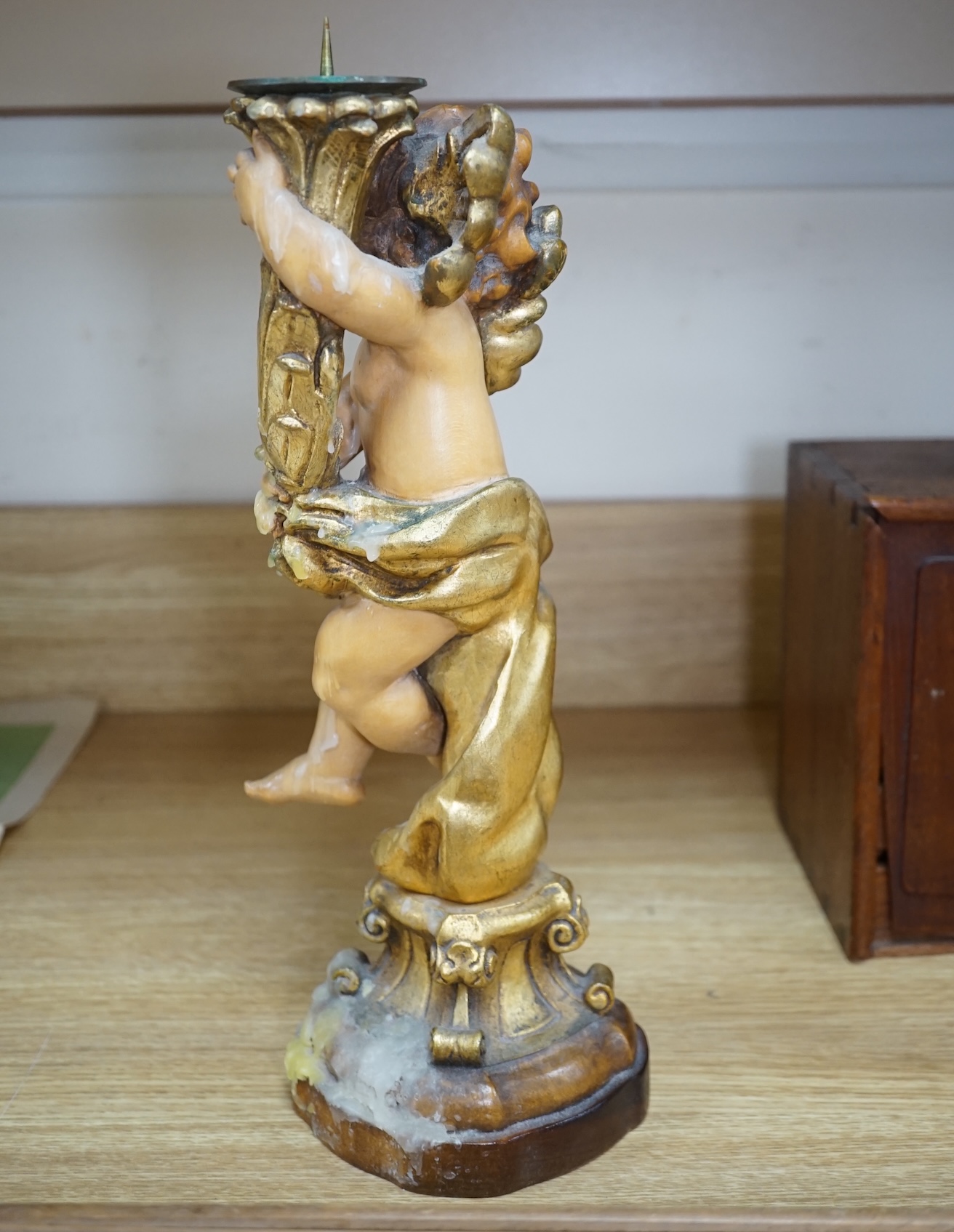 An Austrian carved and partially gilt cherub pricket candlestick, 37cm high. Condition - fair to good